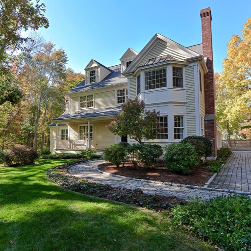 new england colonial style home in the early fall with blue skies green grass and paved walkways